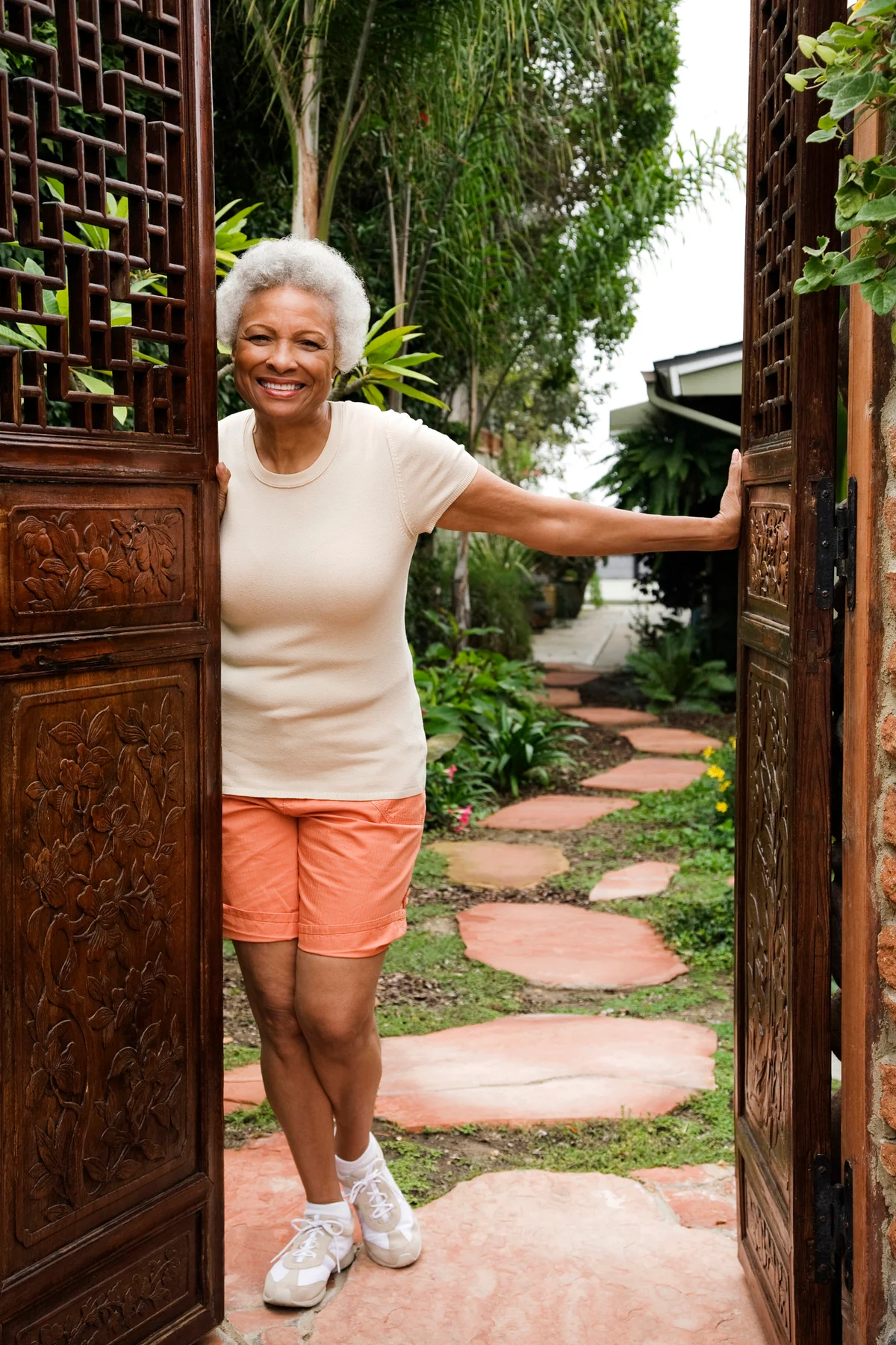 Senior woman opening beautiful old doors in garden