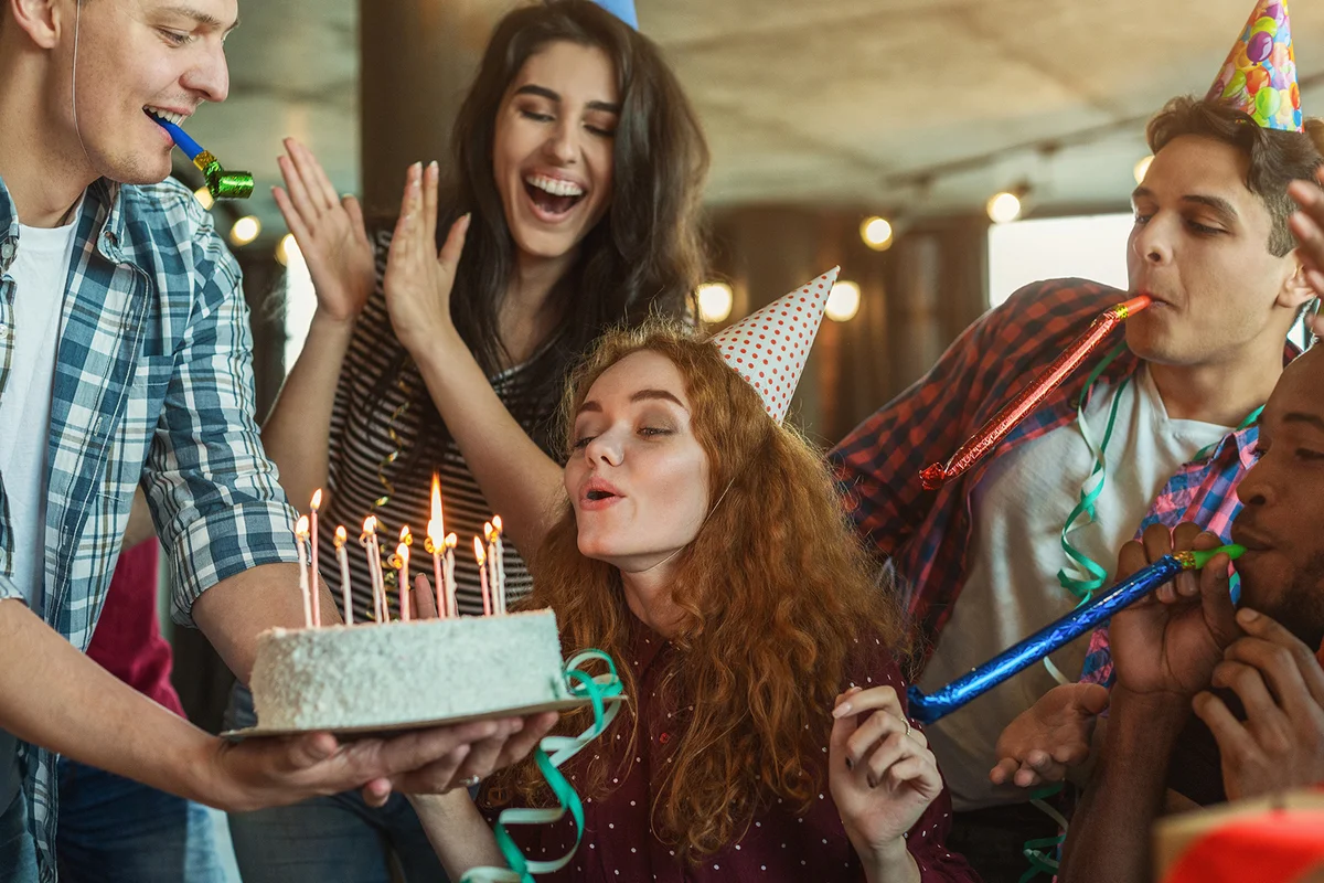 Friends presenting birthday cake to girl