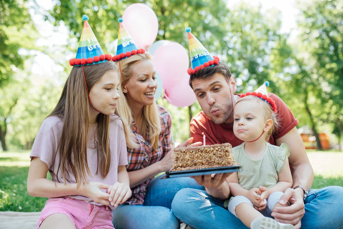 Family blowing out a first birthday candle