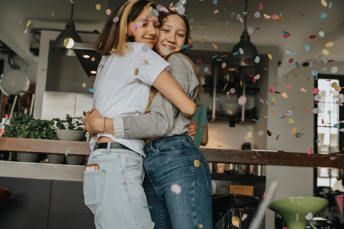 two girls hugging with confetti in foreground