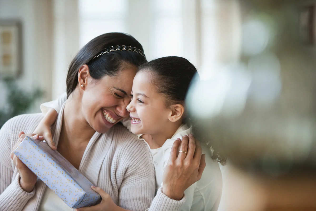 mother and daughter holding a gift and smiling
