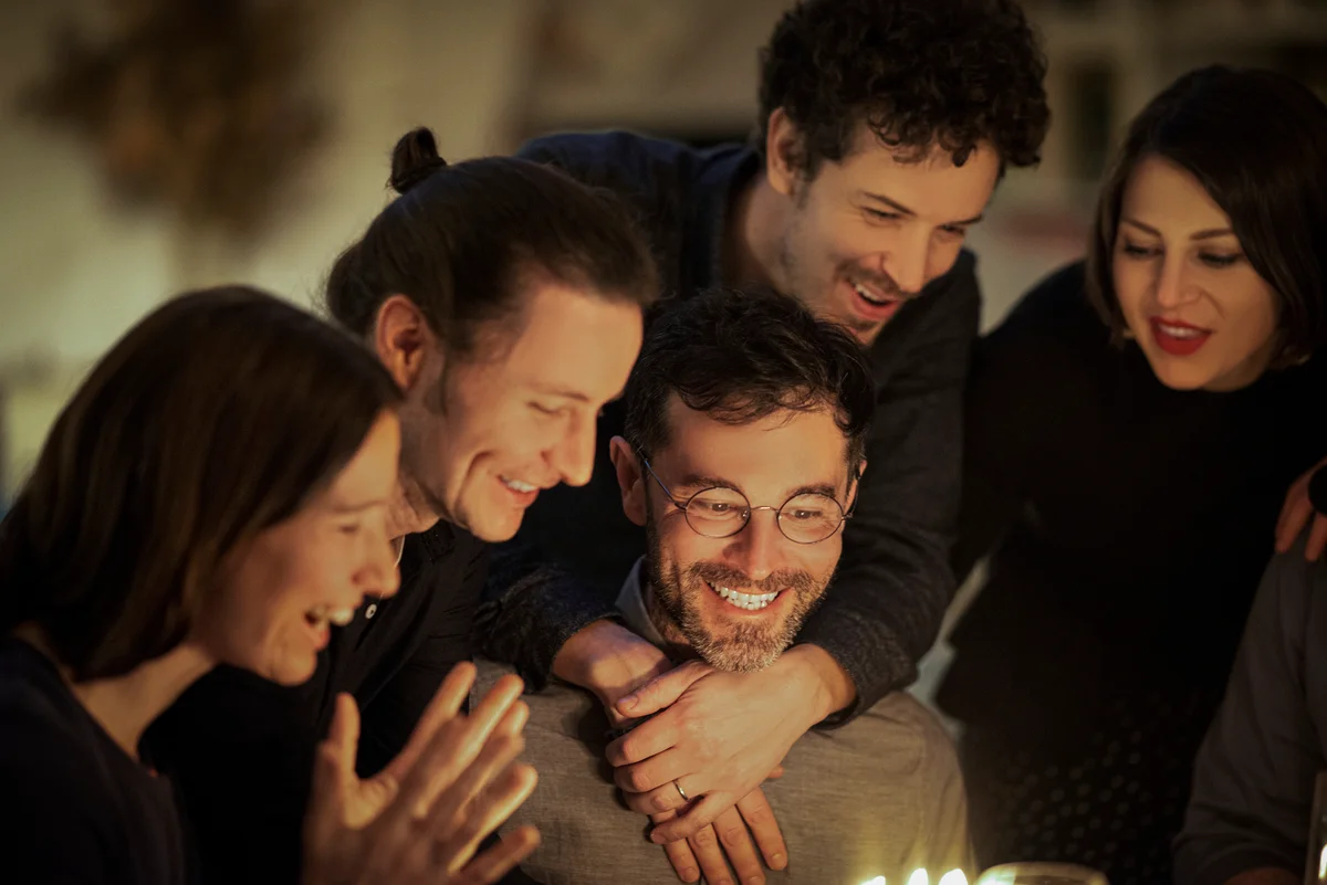 Happy male and women celebrating friend's birthday at home
