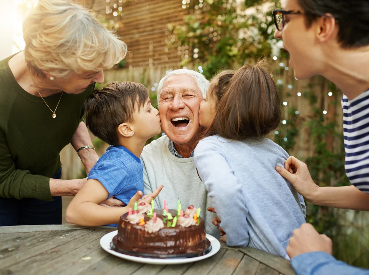 Kids kissing their grandfather on his birthday