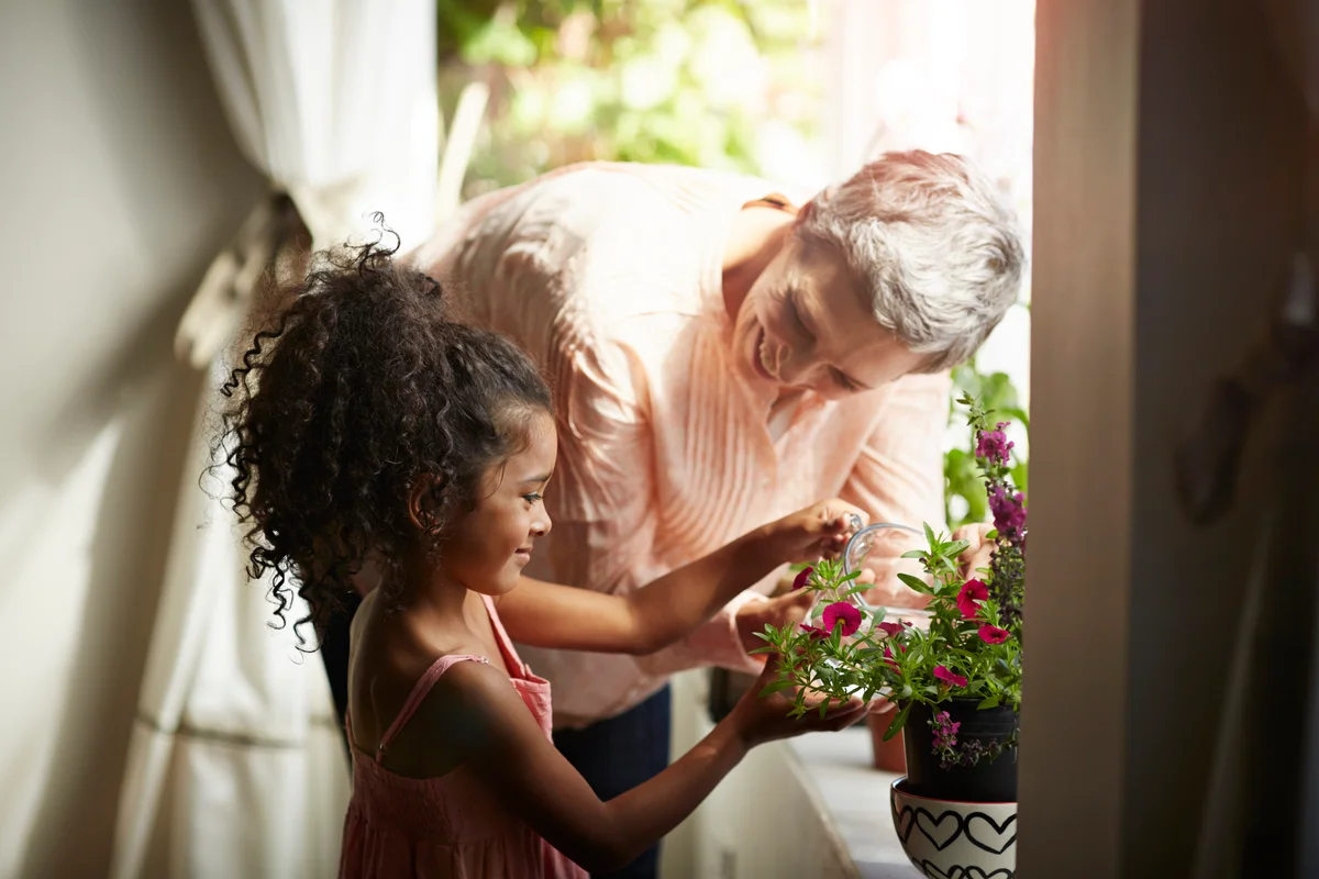 Grandma helping granddaughter tend to indoor flowers