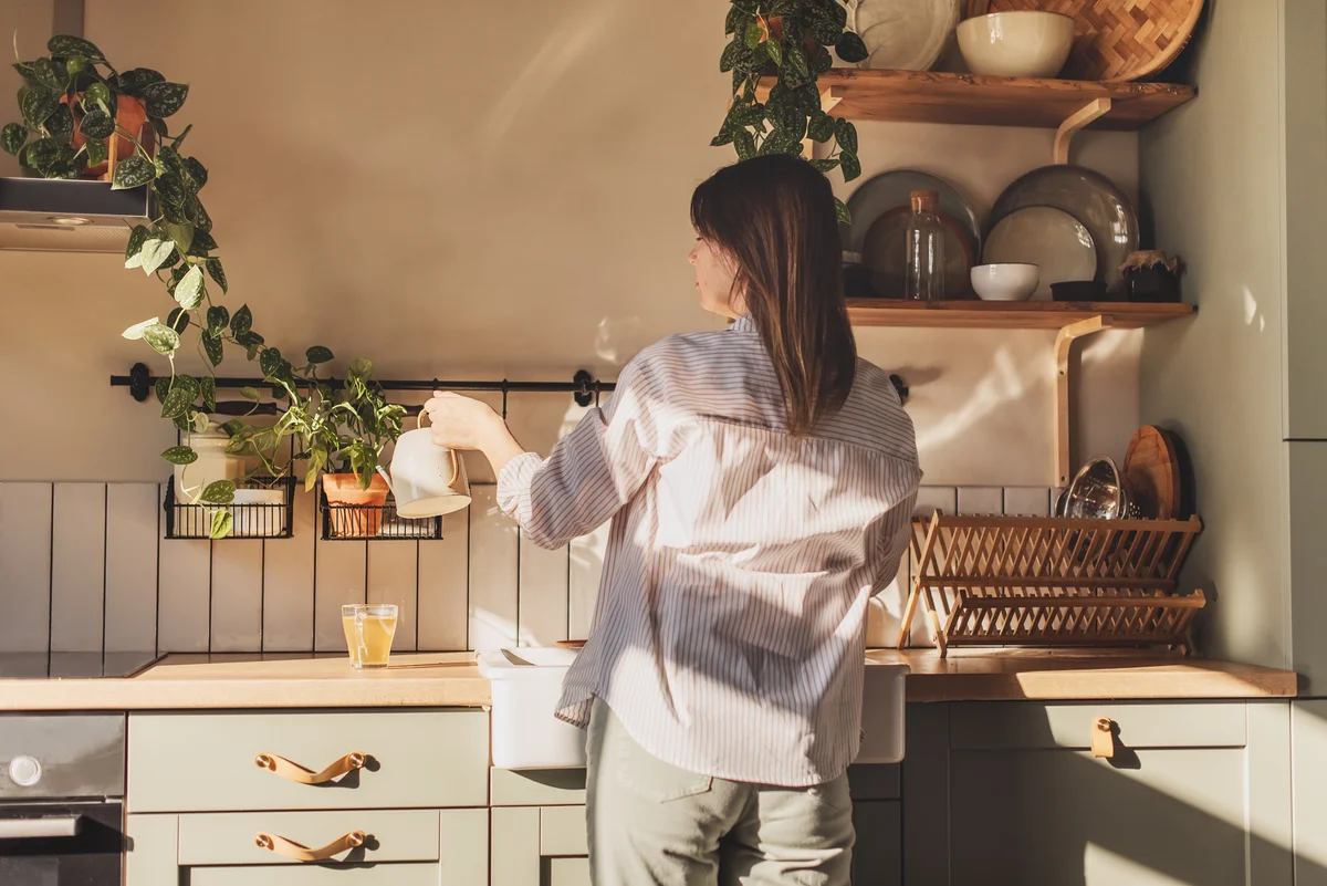 Woman watering plants in her kitchen
