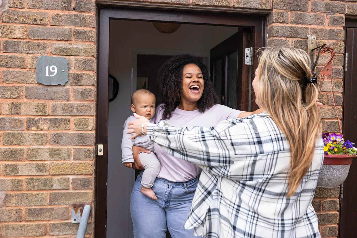 mother holding her baby whilst standing in her doorway