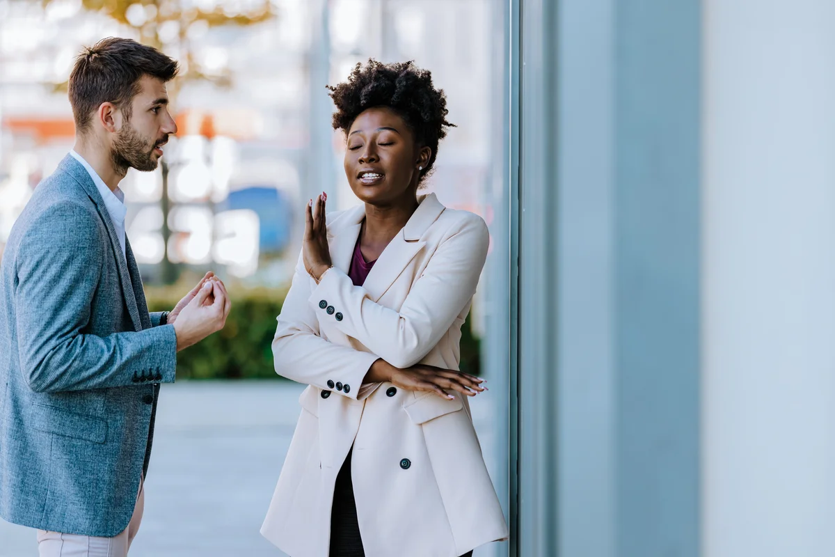 Woman putting her hand up to man as if she won't listen to what he says