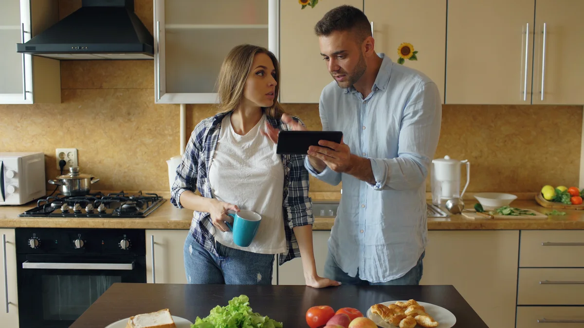 Man showing woman something iPad while she looks annoyed