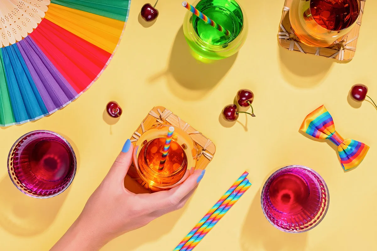 Colorful cocktails on yellow table for rainbow party with rainbow drinking straws and party accessories