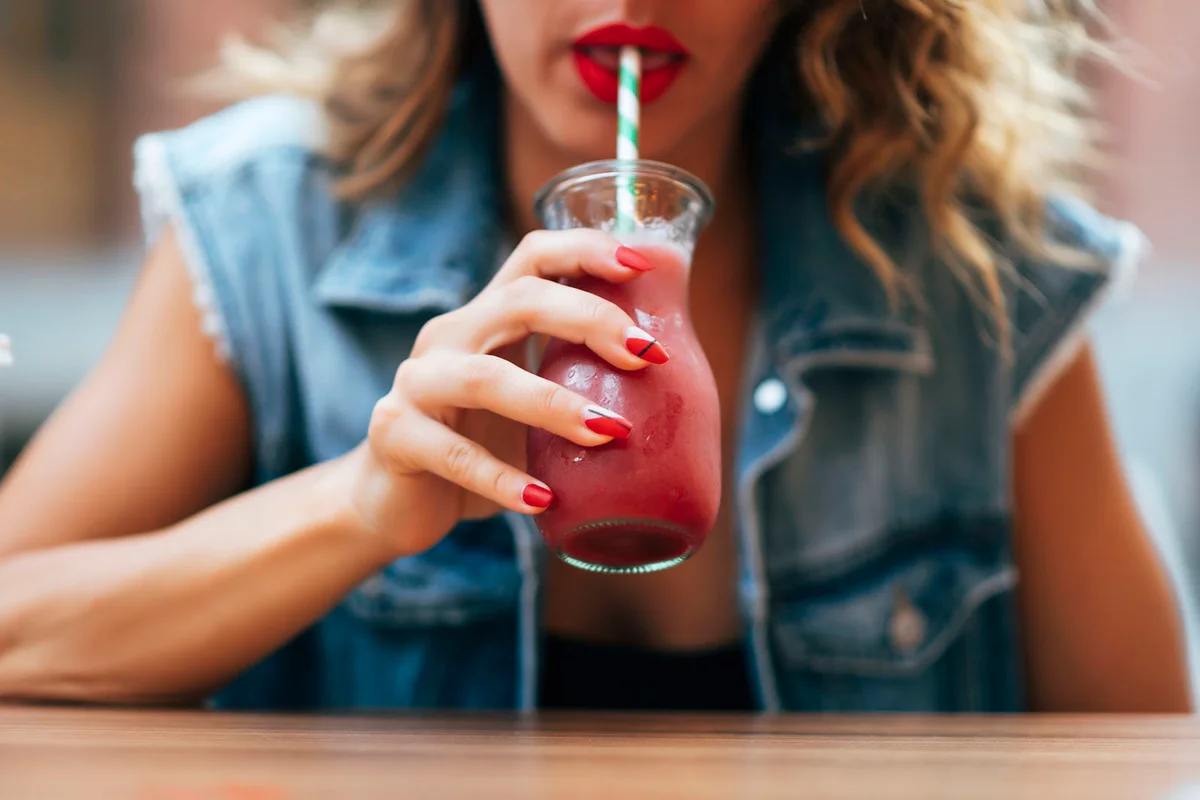 Pretty woman red lips drinking a cocktail soda