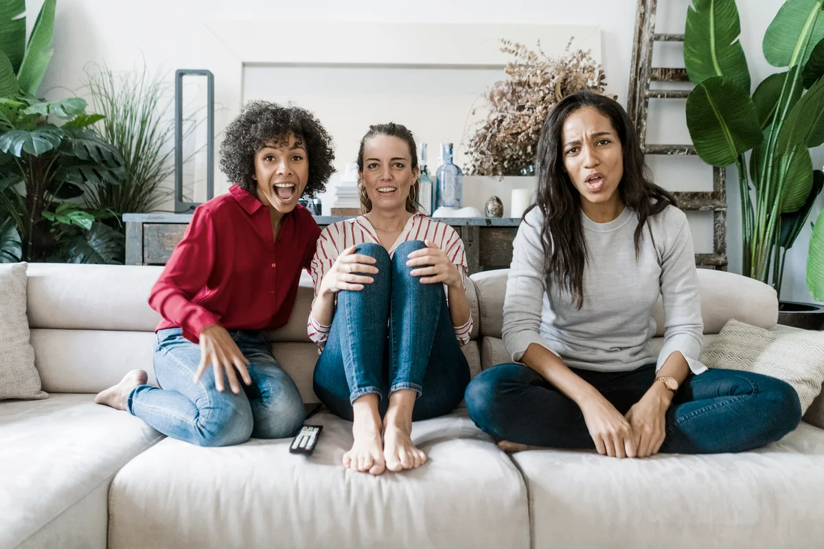 Three women on couch at home watching Tv