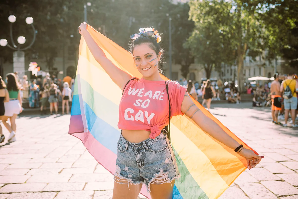 Young female protester with rainbow flag on footpath