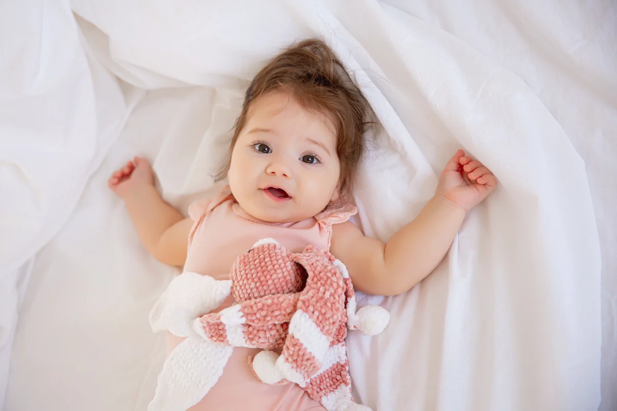 Baby girl is lying on the bed at home