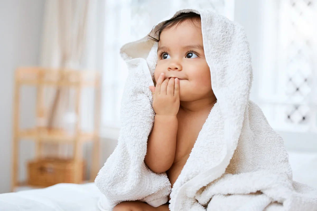 Adorable baby girl covered in a towel after bath time