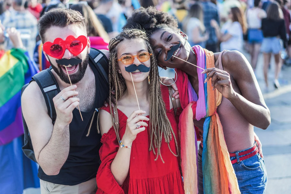 Cheerful young people with paper mustaches at the pride festival