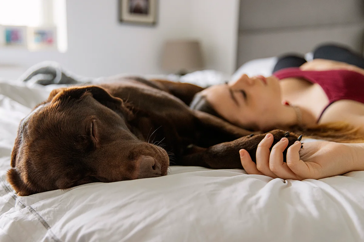 Teenage girl asleep on bed with her pet dog