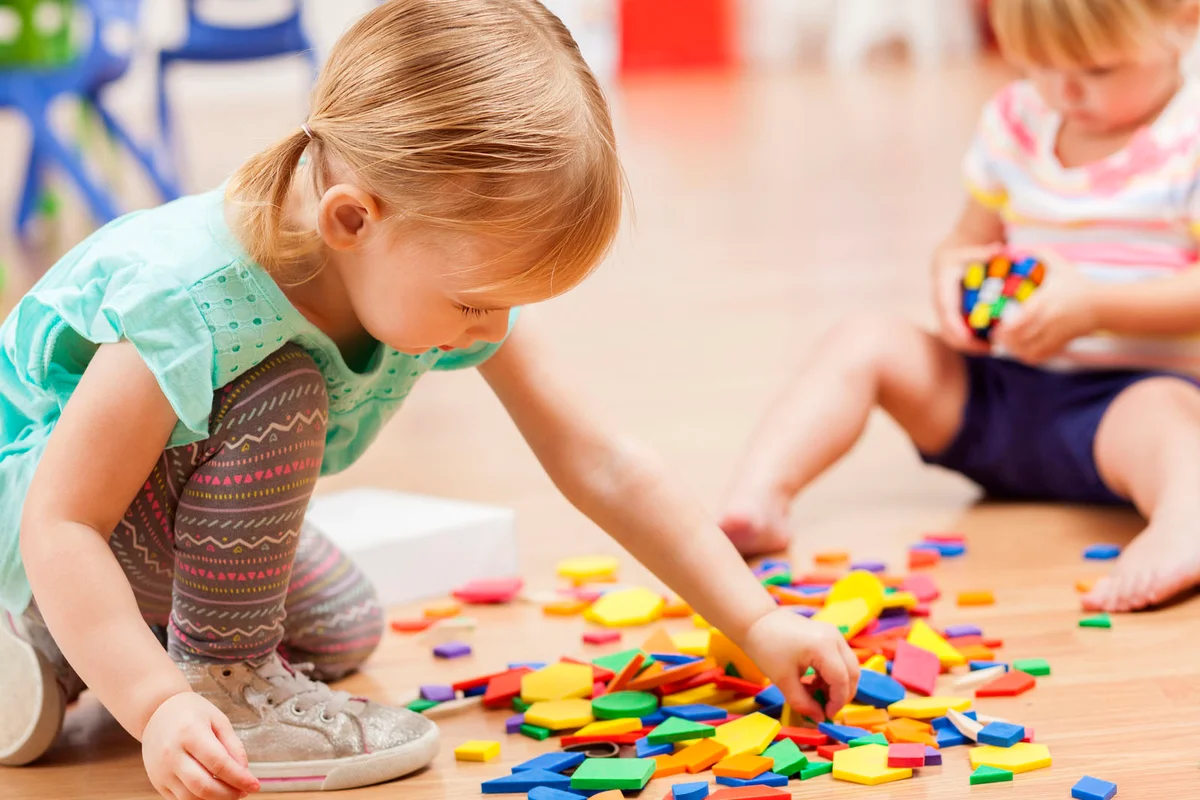 Toddler girls playing with puzzle pieces