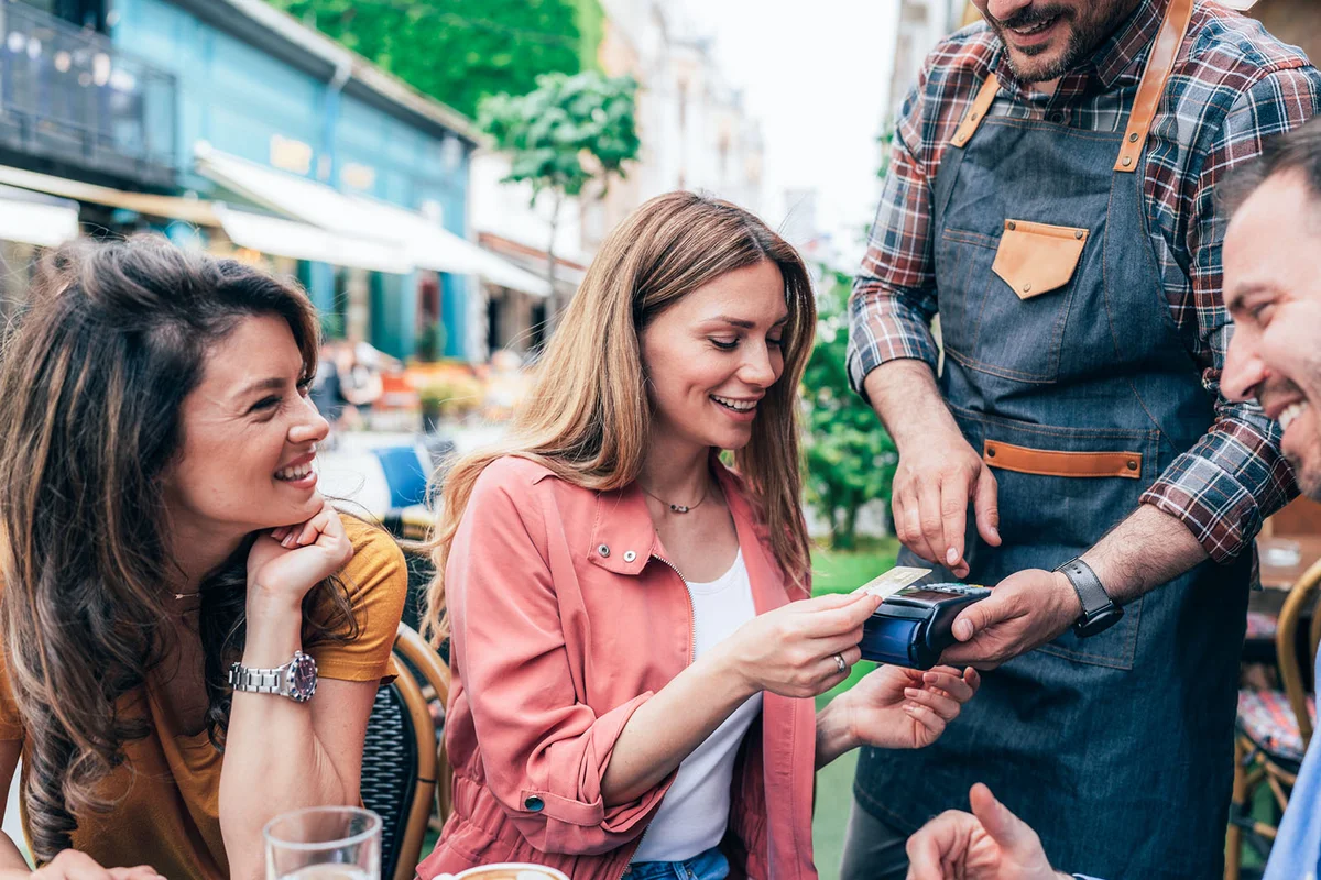 oung woman paying contactless using credit card in sidewalk cafe,