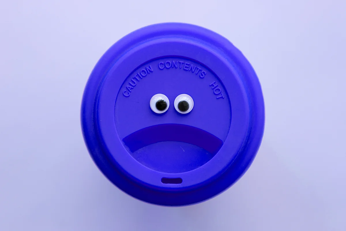 The lid of a keep cup with a funny face.