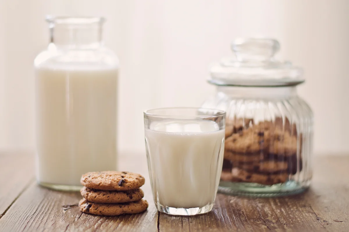 Chocolate chip cookies with milk on rustic wooden table