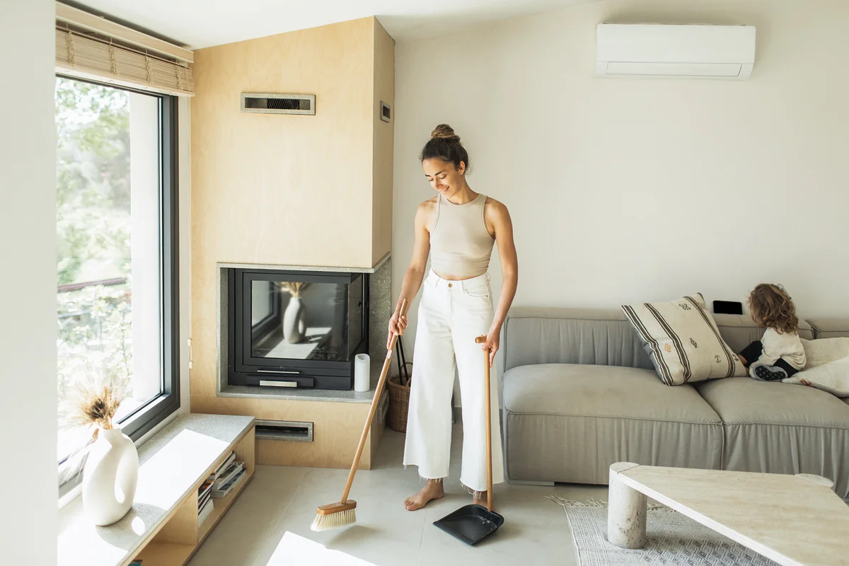 Young woman sweeping the floor and cleaning house