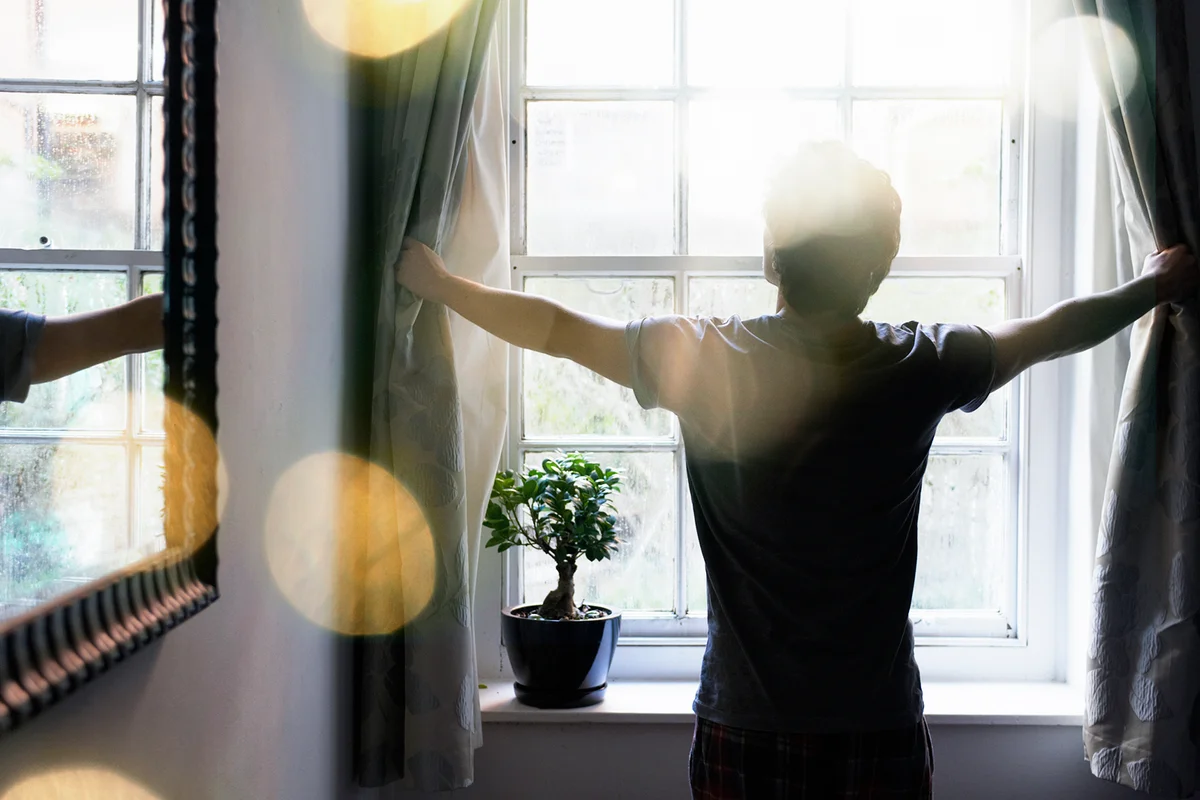 Man opening curtains in the morning