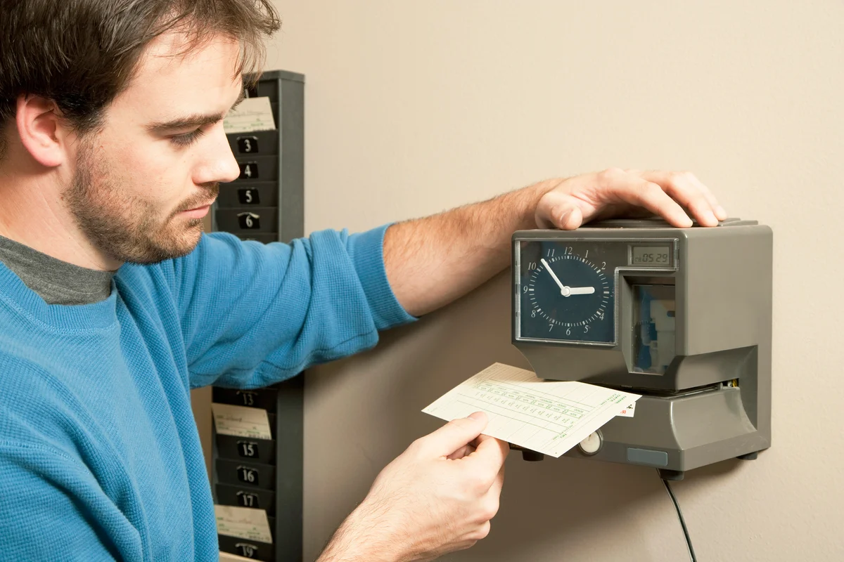 Man marking payroll record with time clock