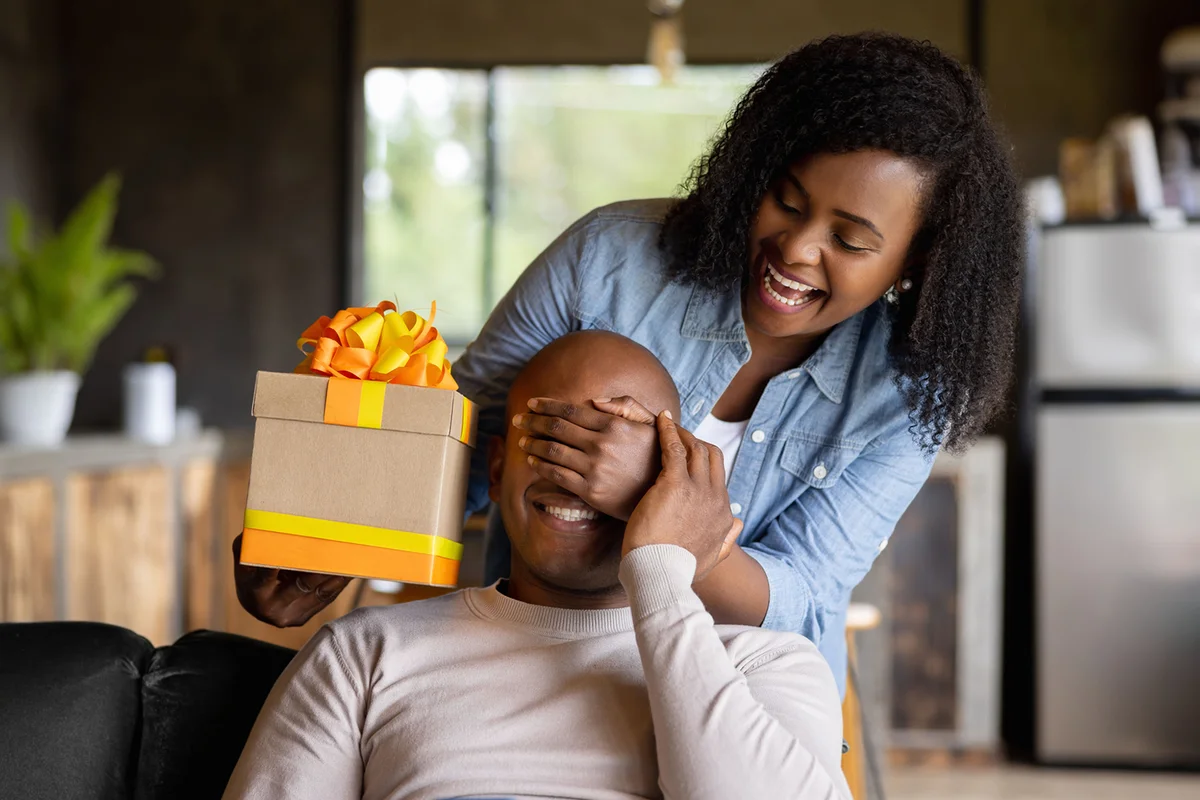 Woman at home surprising her husband with a gift