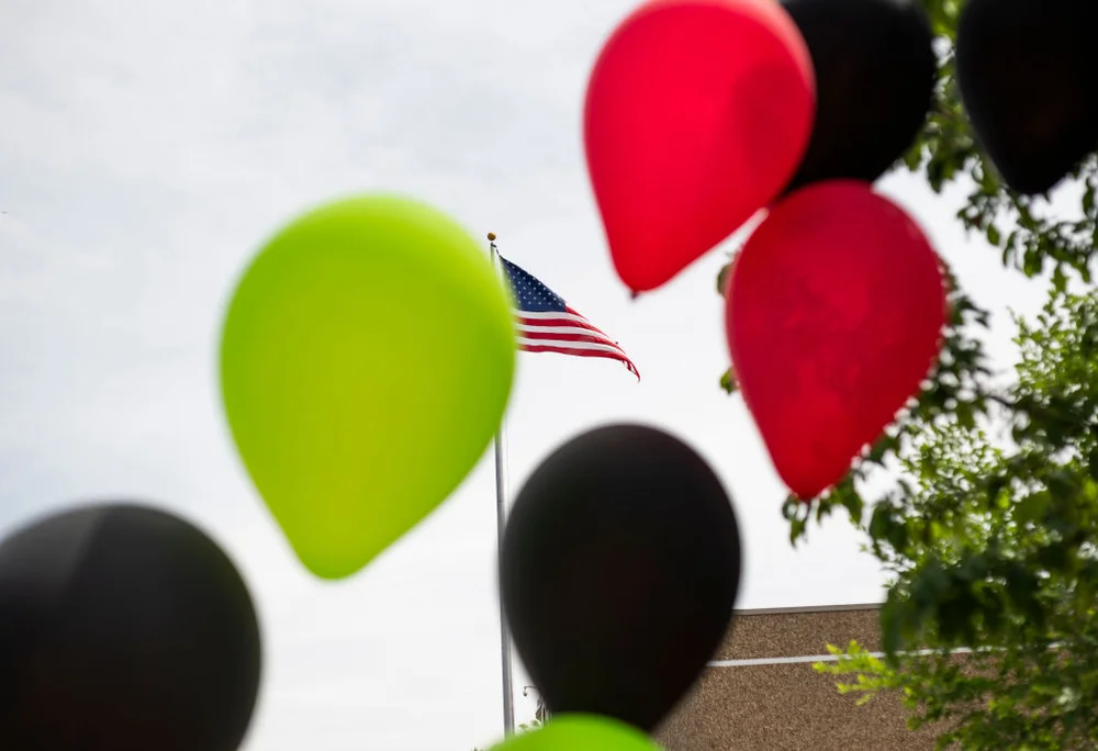 MINNEAPOLIS, MN - JUNE 19: An American flag flies in the background as red, black, and green balloons set up for a Juneteenth celebration blow in the wind on June 19, 2020 in Minneapolis, Minneapolis. Juneteenth commemorates June 19, 1865, when a Union general read orders in Galveston, Texas stating all enslaved people in Texas were free according to federal law.