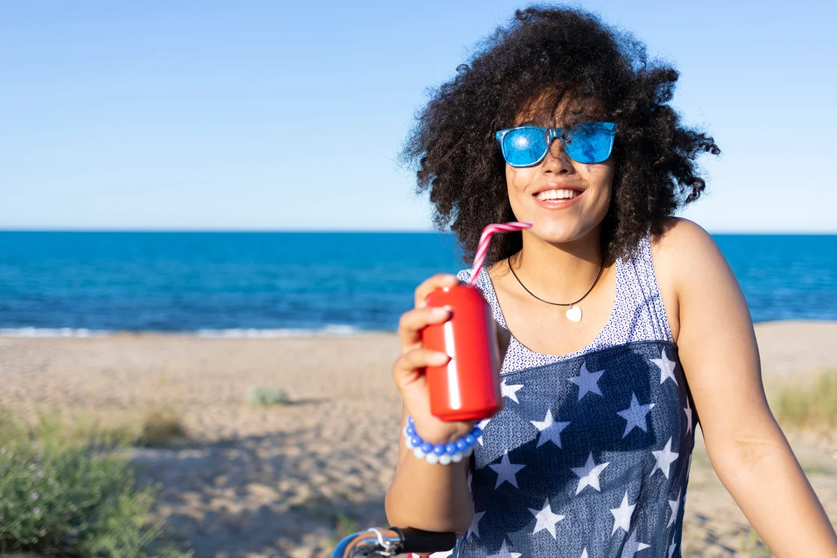 Carefree woman drinking red can on beach