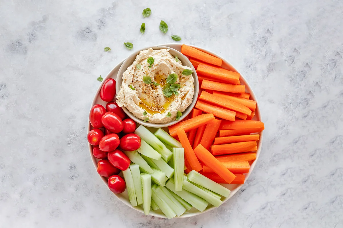 hummus with cherry tomatoes, carrot and cucumber batons
