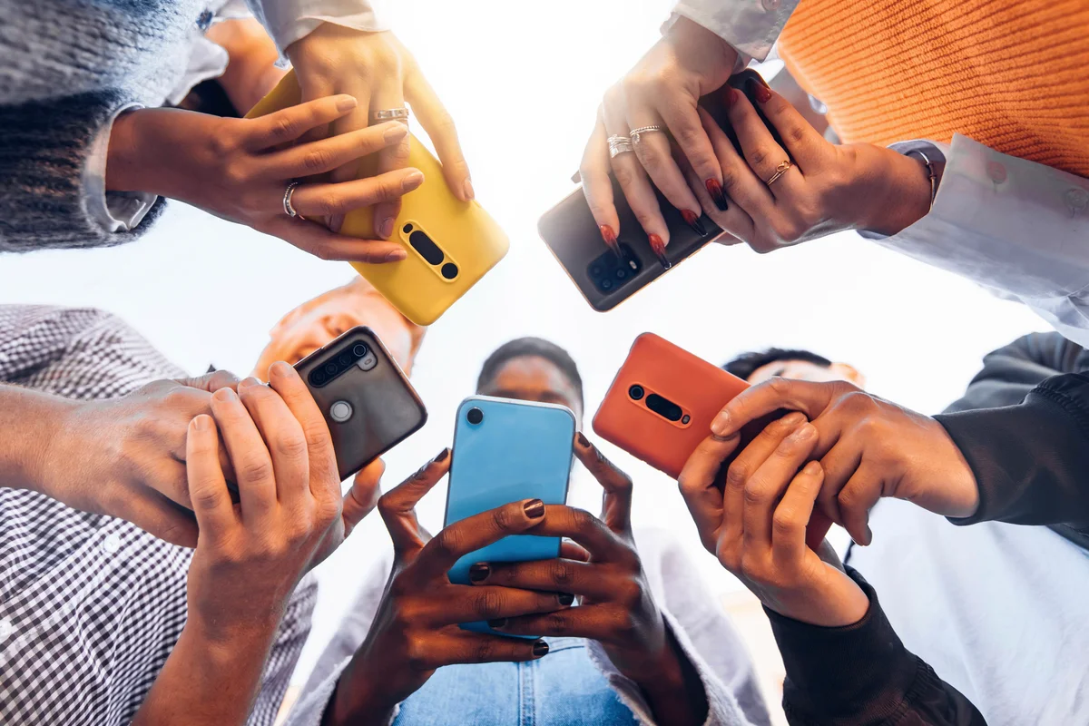 Teens in circle holding smart mobile phones
