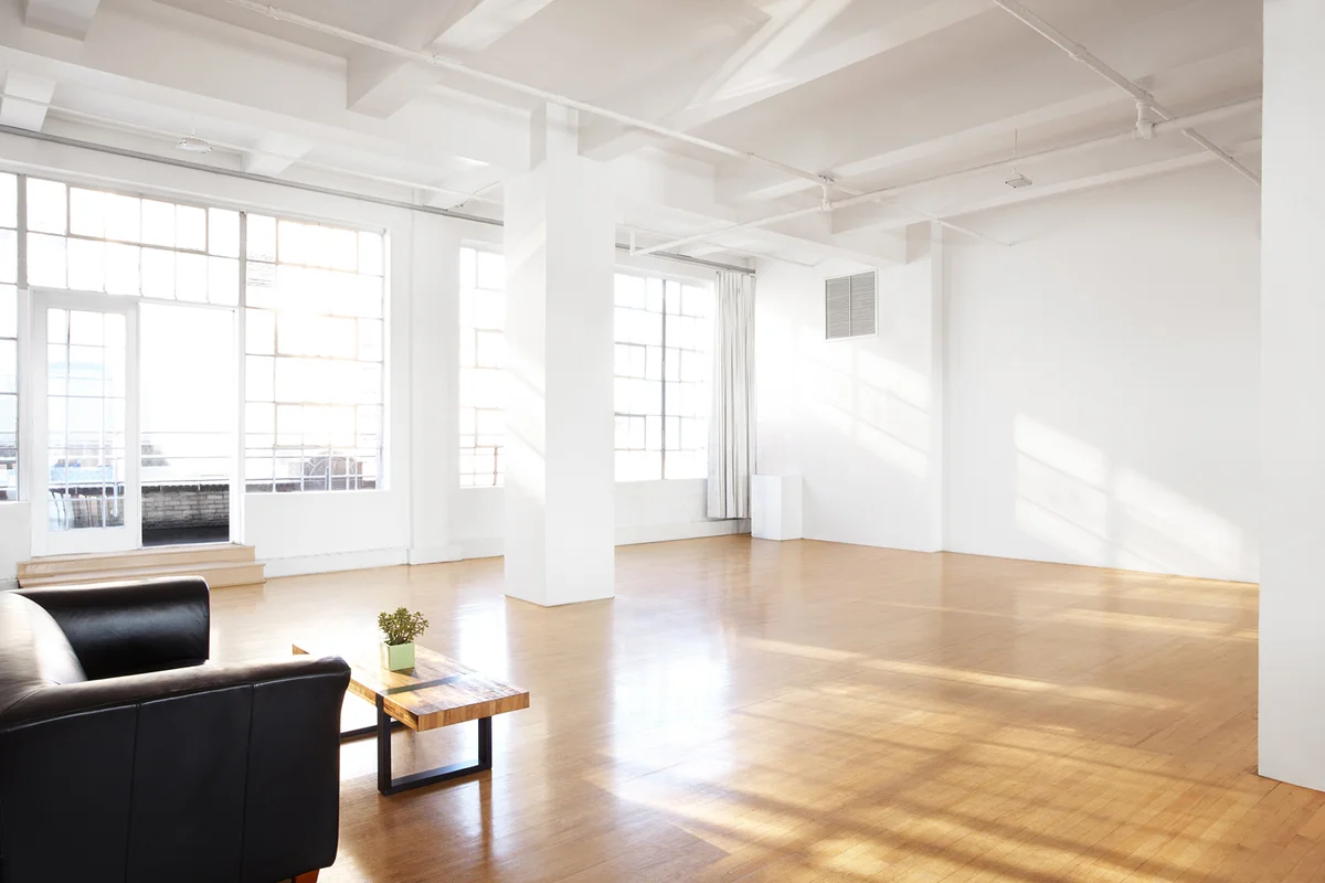 large bar room with cascading light coming in through large windows & a couch to sit at