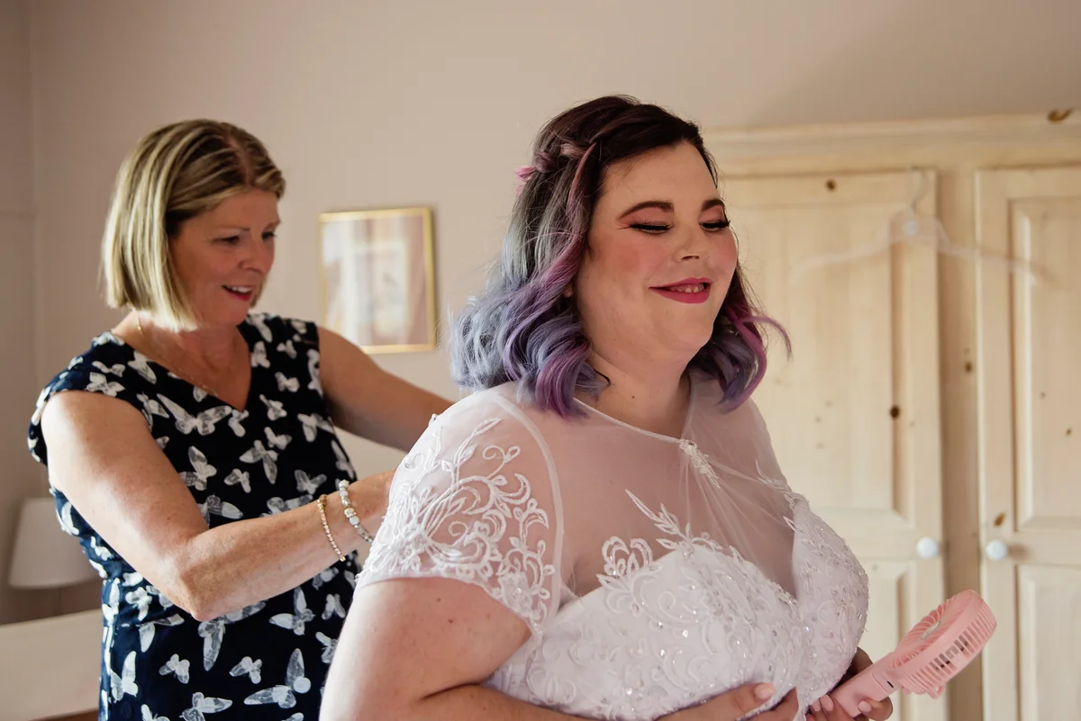 mother helping bride get dressed