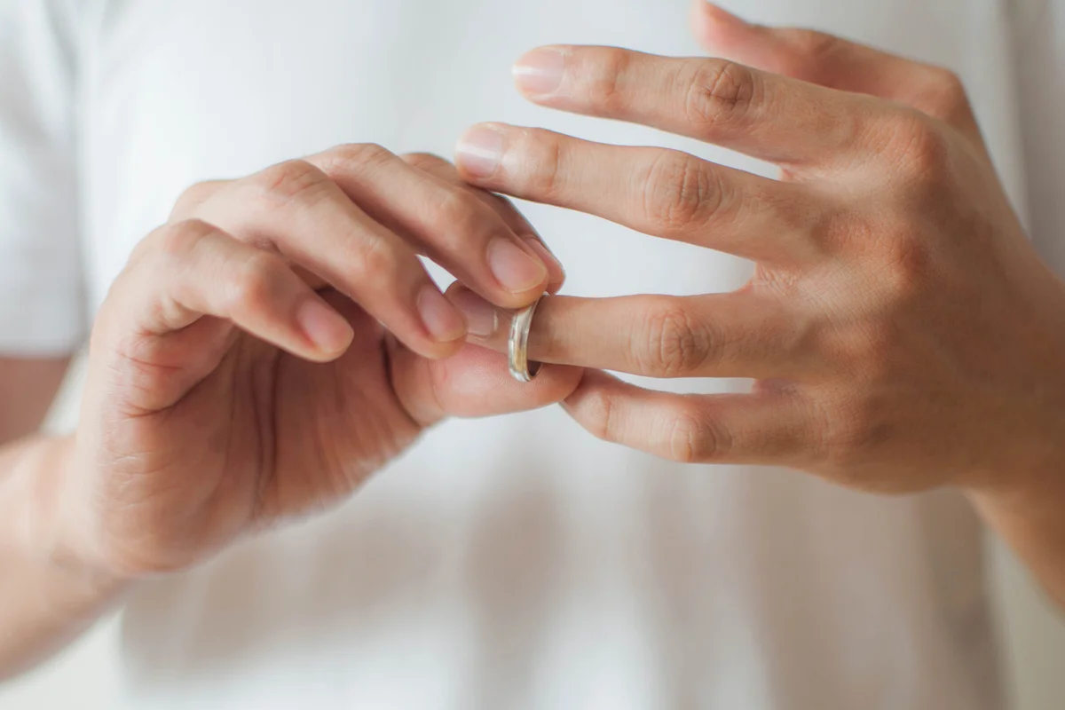 A young man is removing his wedding ring