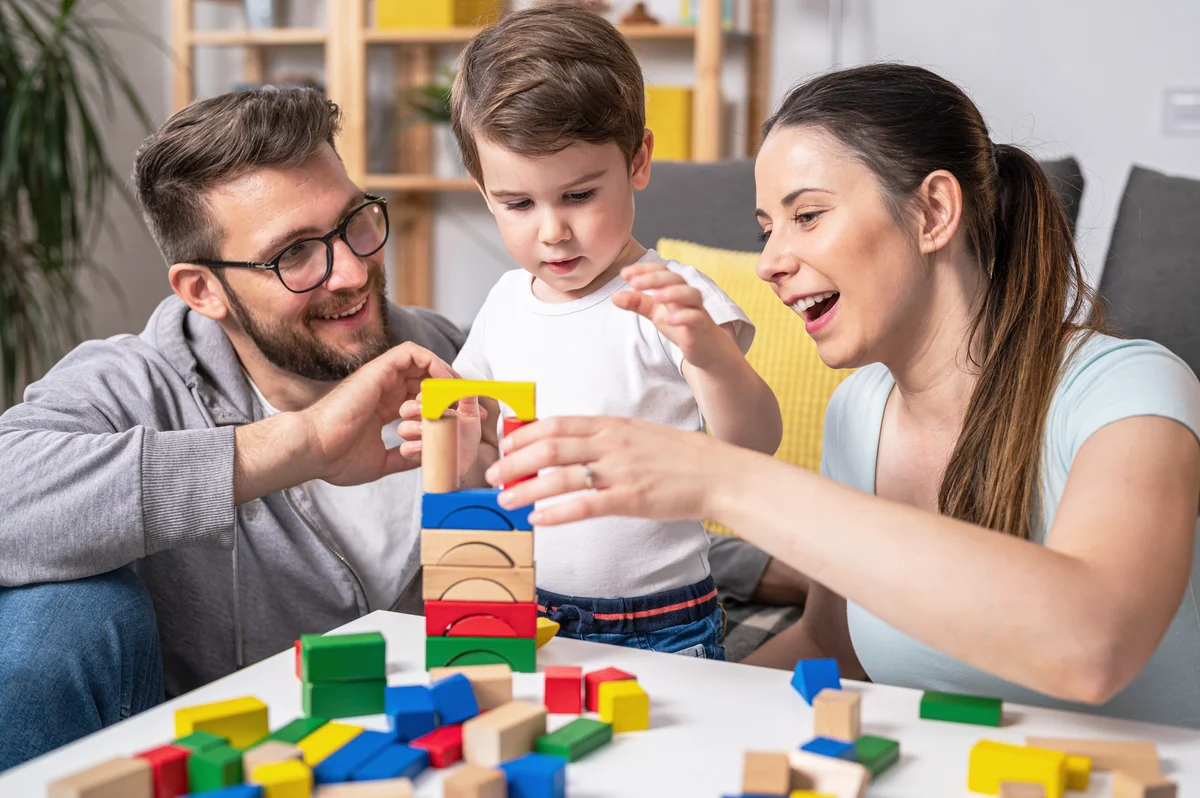 Mother and father playing with toddler using didactic wooden toys