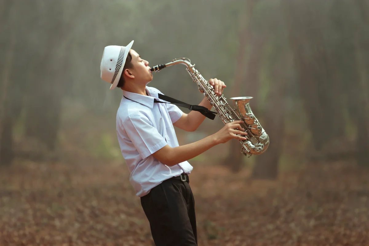 Young man playing Saxophone in the forest