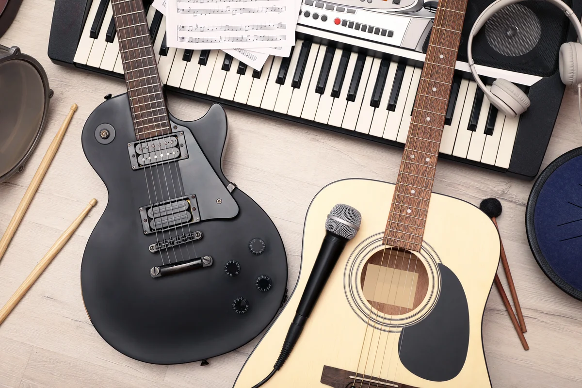 Different musical instruments, headphones and microphone on wooden background