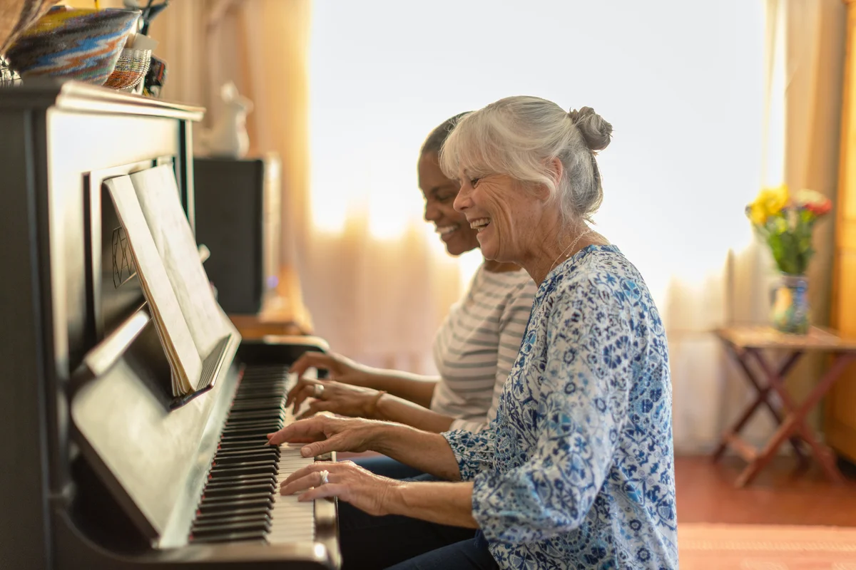 Two women playing the piano together at home