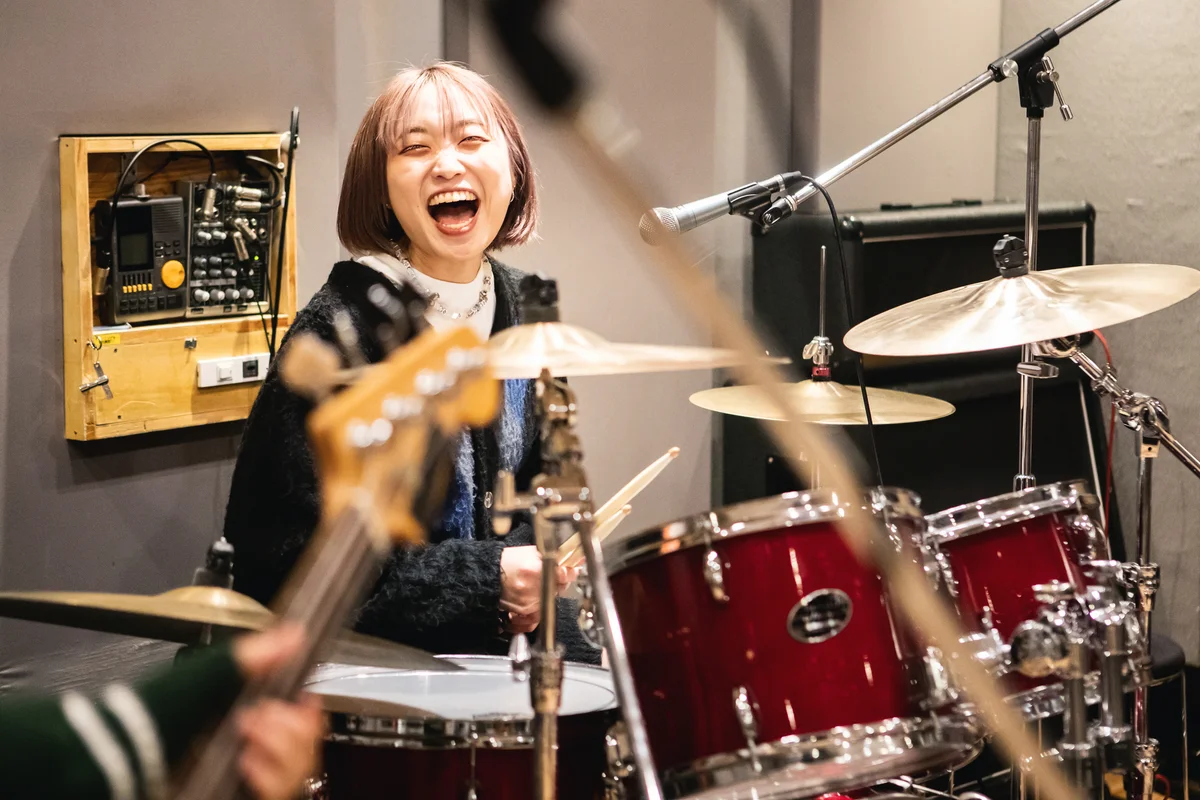 Female drummer laughs while practicing in a music studio