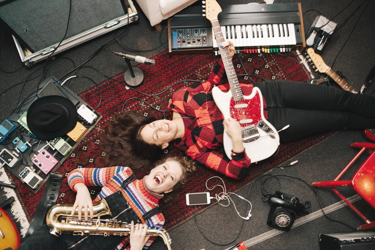Happy musicians playing instruments while lying on carpet