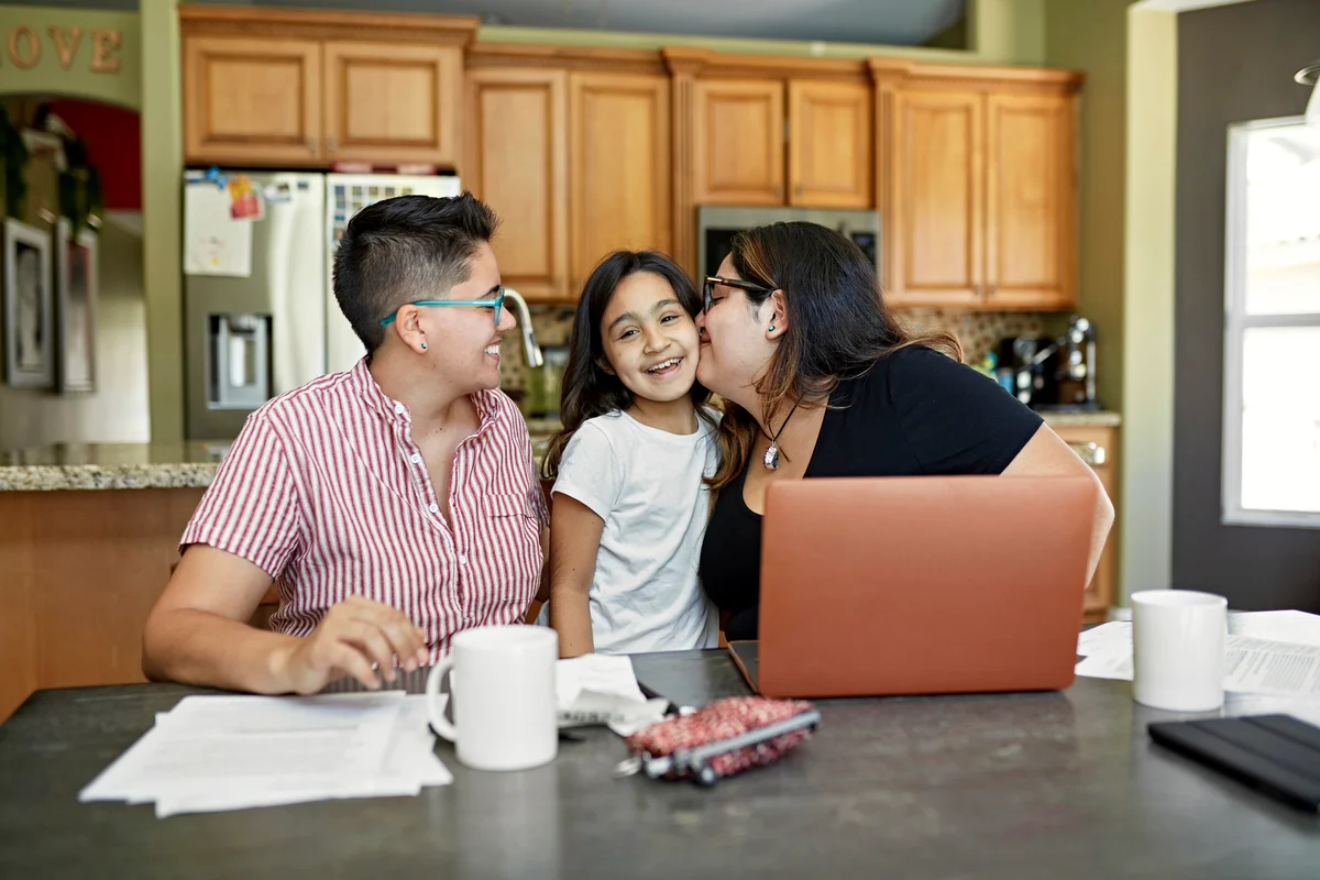 Two moms and daughter as they plan budgeting for vacation in the kitchen