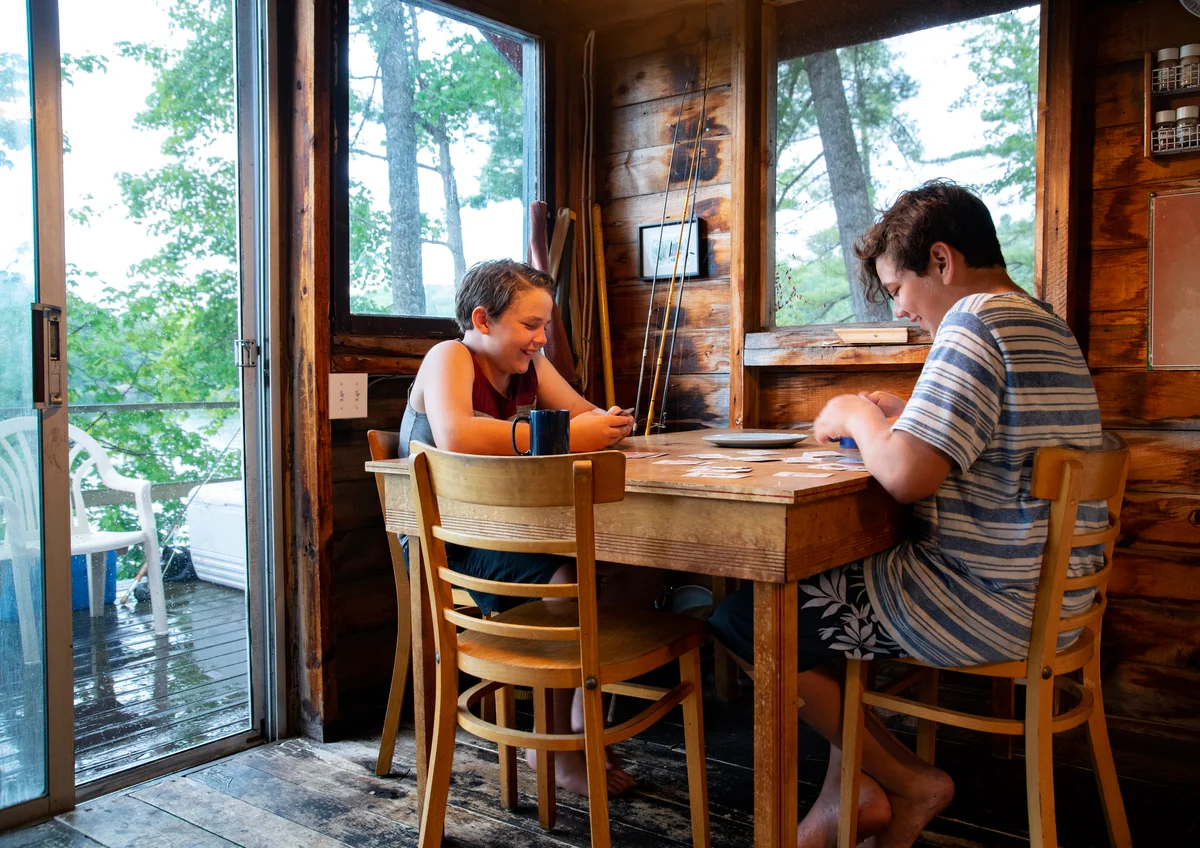 Family playing cards in cabin while it rains outside