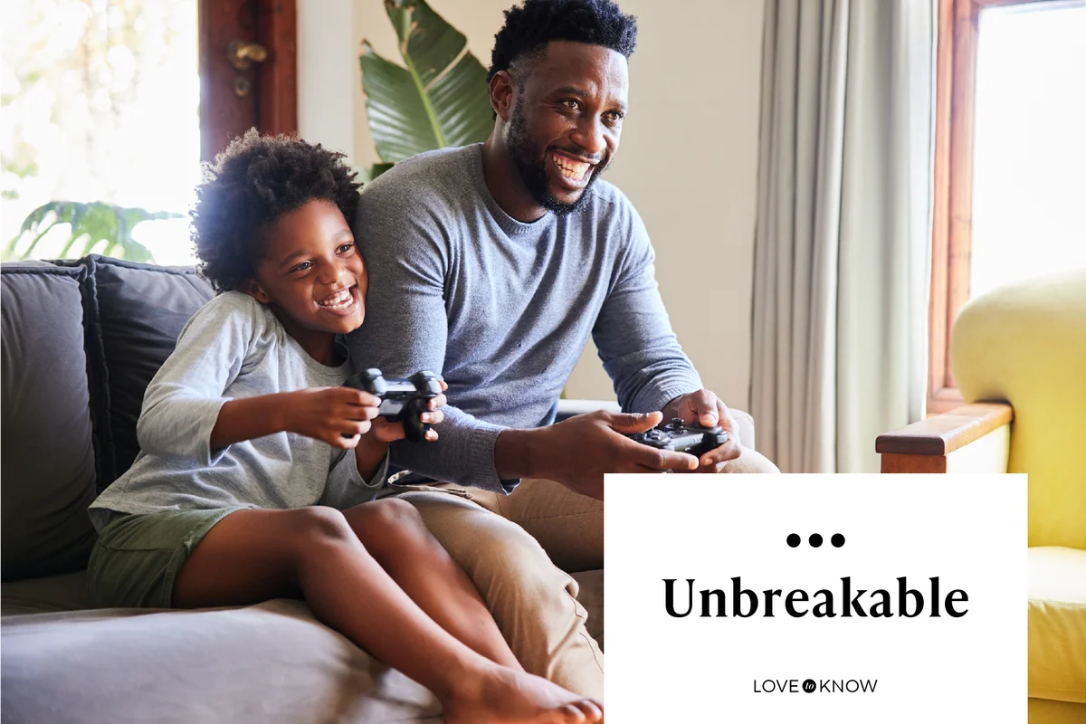 Cute boy and his dad playing video games together at home