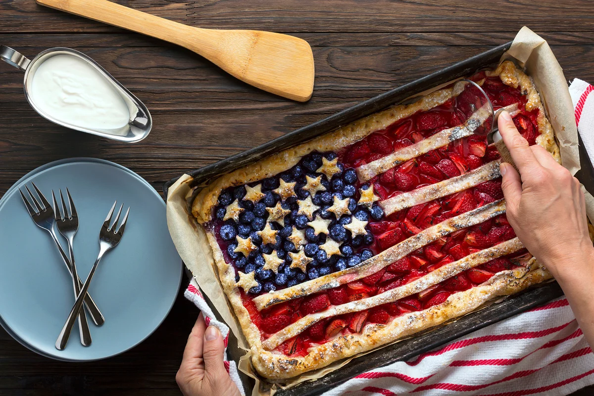 A woman cuts a berry pie in the form of an American flag