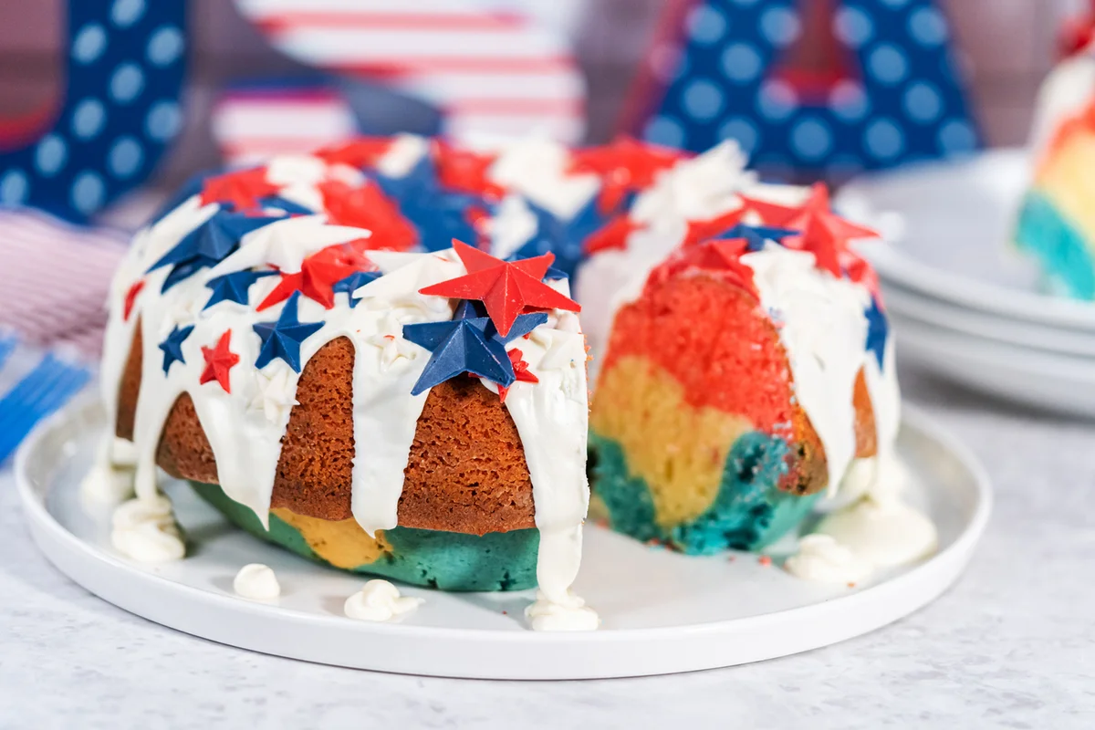 Slicing July 4th bundt cake covered with a vanilla glaze and decorated with chocolate stars