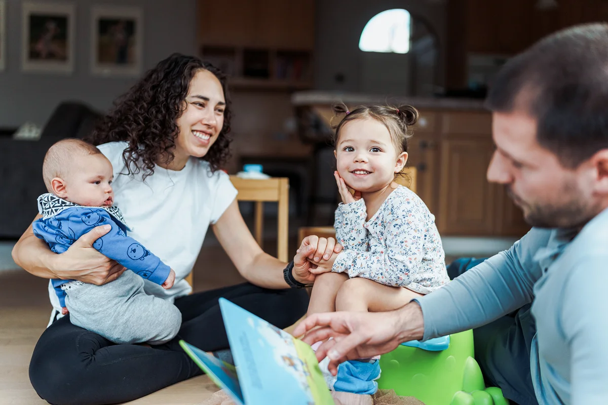 Supportive parents teaching toddler daughter to use the potty