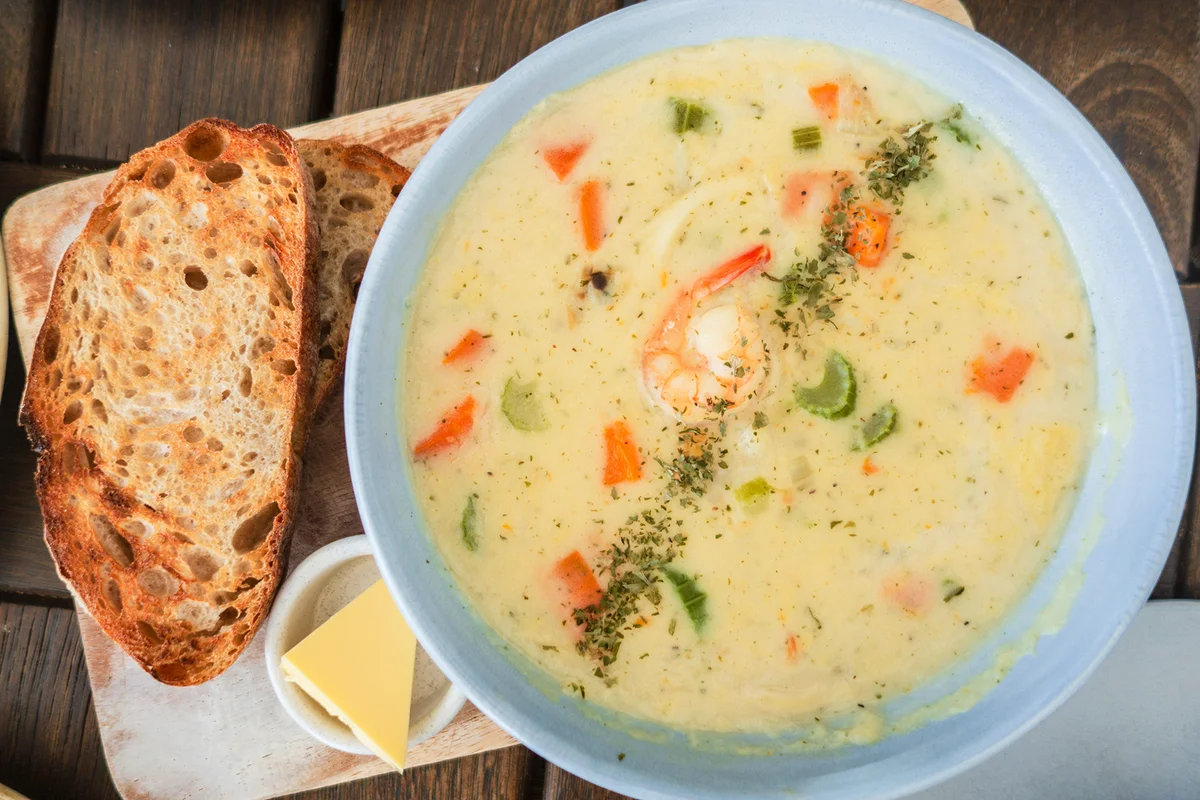 Table top view of Seafood Chowder with bread and butter.