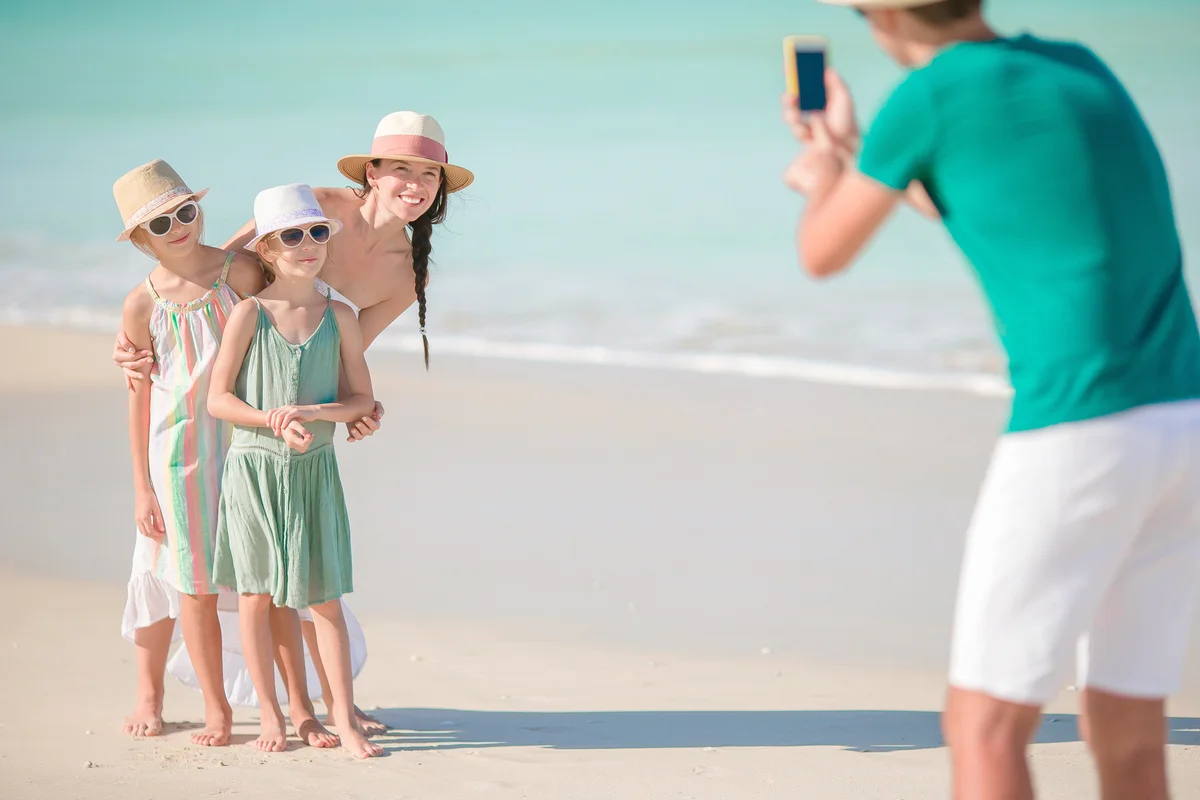 Man taking a photo of his family on the beach