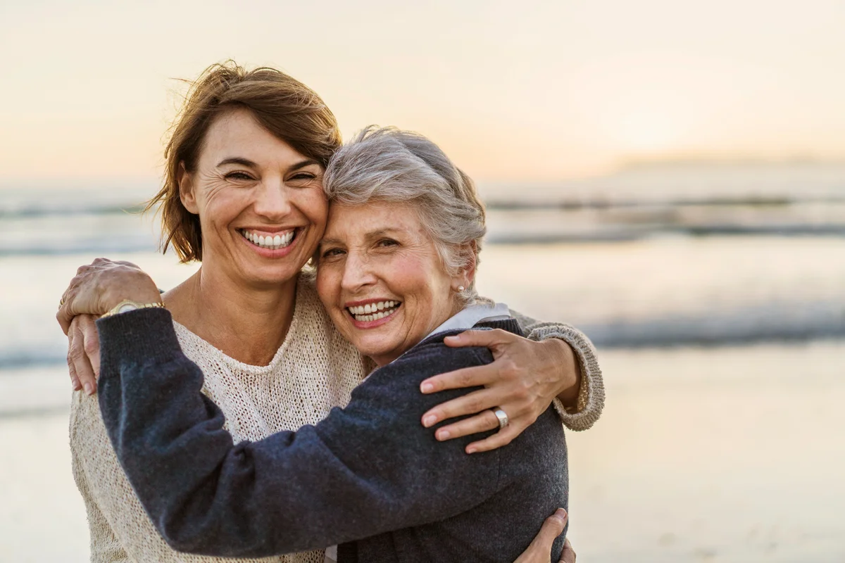 Happy daughter embracing senior mother at the beach